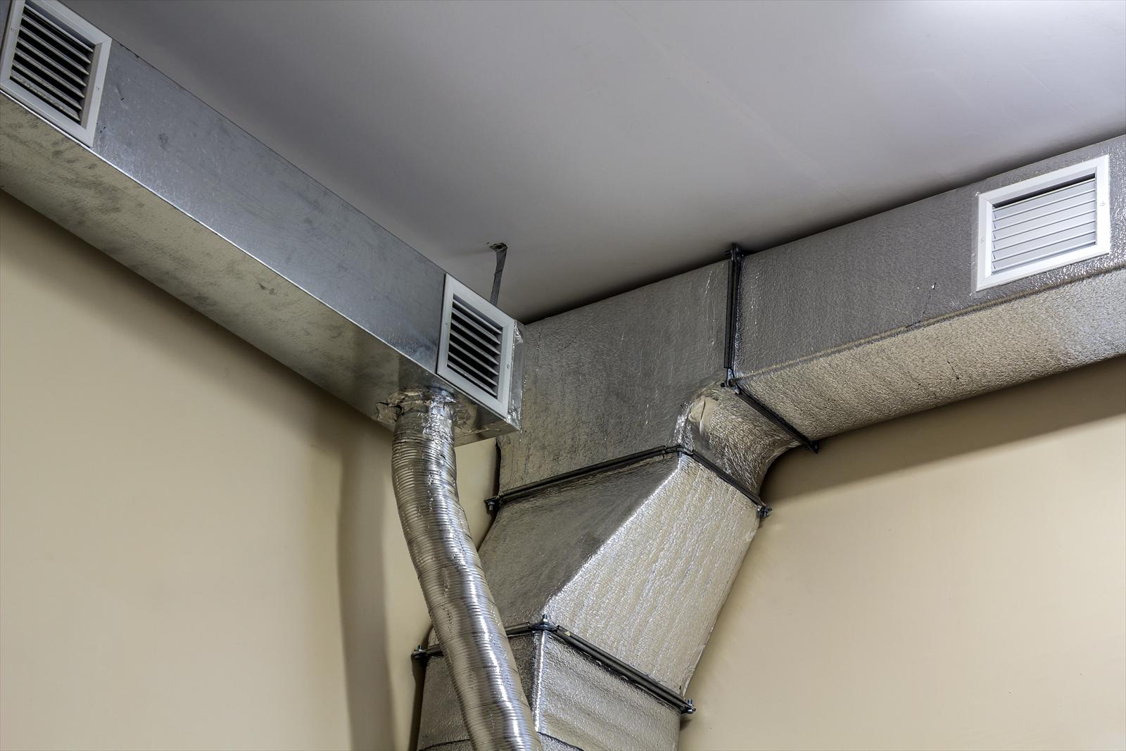 Exposed sheet metal air ducts and supply registers running along a ceiling